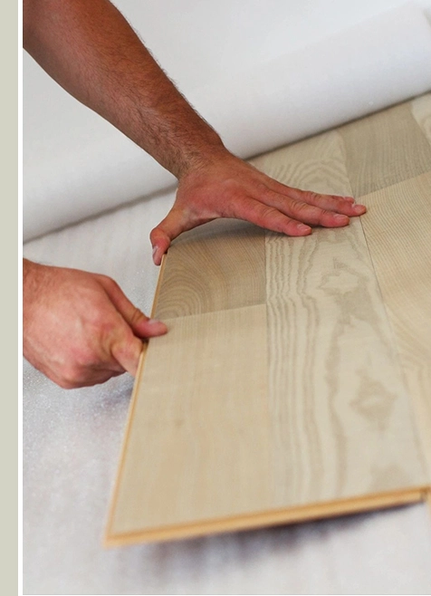 A person is holding the floor board of a piece of wood.